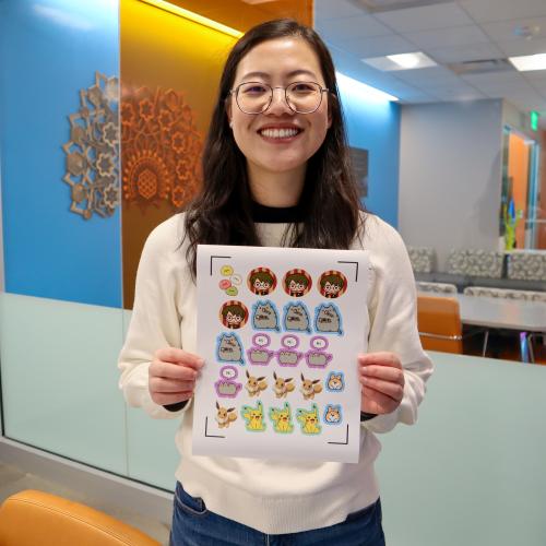 Anni holding a sheet of stickers she printed out with the Cricut.