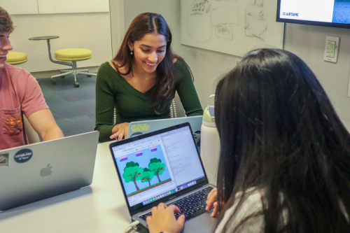 two young women on laptops, one is smiling